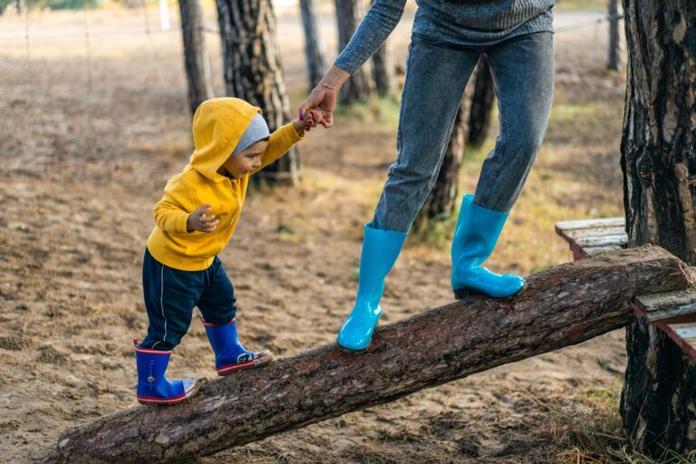 Child being led up a log by parent
